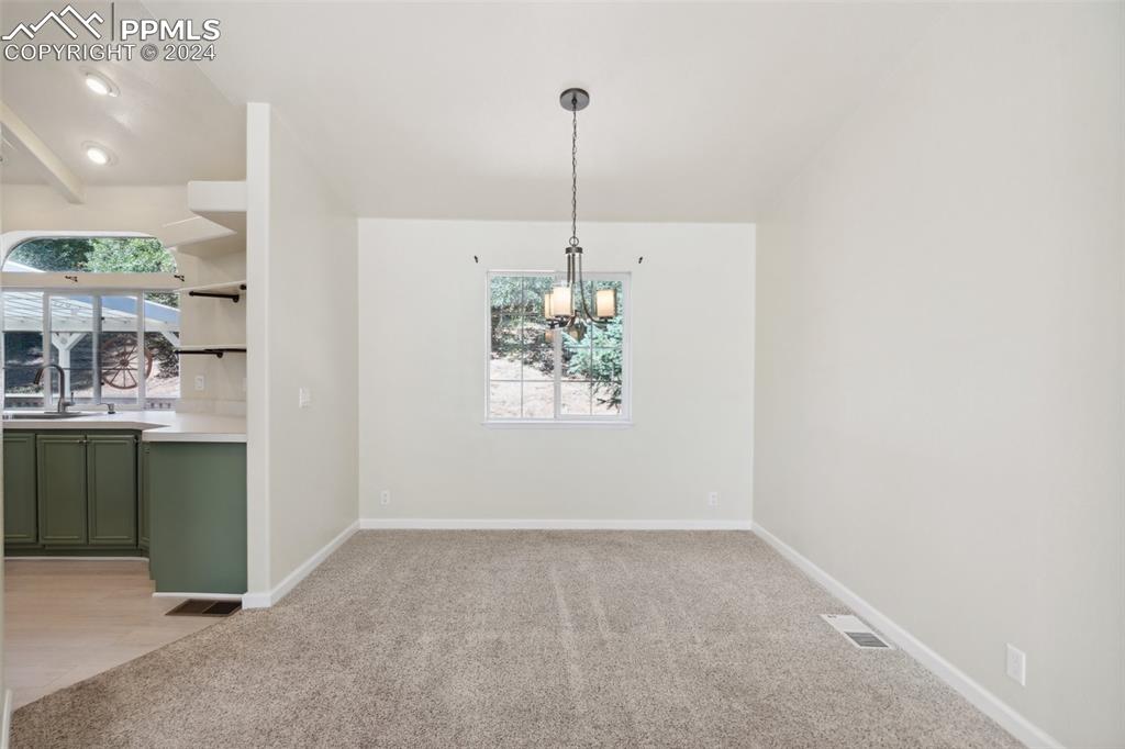 Dining area with an inviting chandelier, sink, and light colored carpet