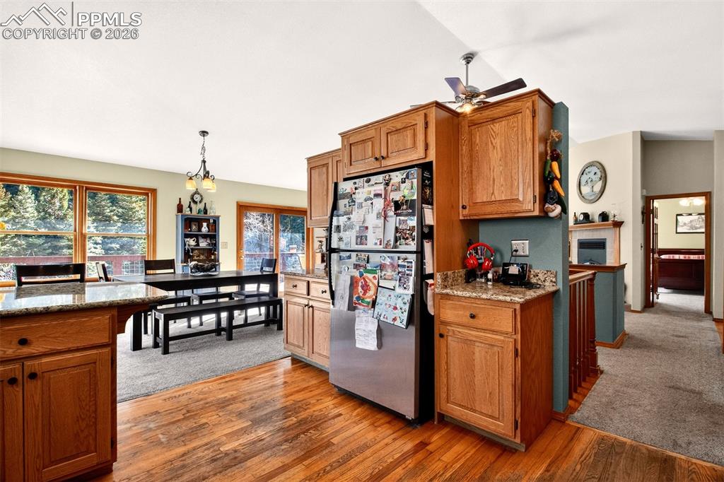 Open concept kitchen with granite countertops, stainless appliances vaulted ceilings, wood floors and a breakfast bar