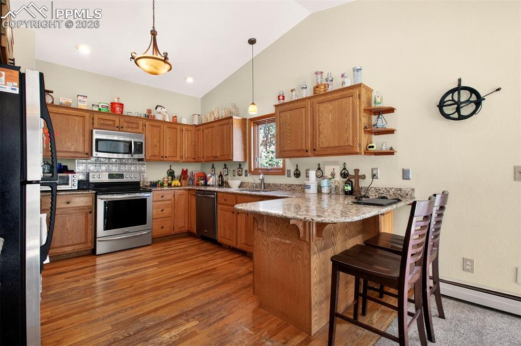 Kitchen with stainless appliances, breakfast bar, granite counter tops and wood flooring.
