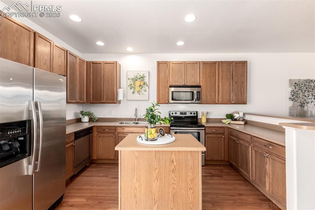 Kitchen featuring stainless steel appliances, light countertops, a kitchen island, light wood-style flooring, and recessed lighting