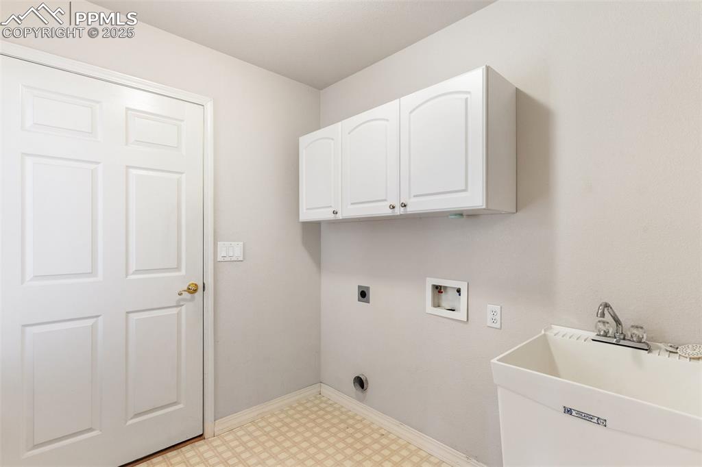 Laundry room featuring light floors, washer hookup, cabinet space, electric dryer hookup, and baseboards