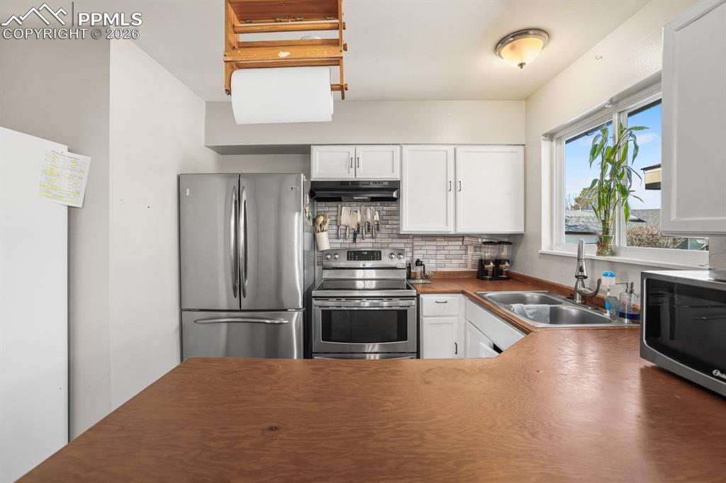 Kitchen with white cabinetry, stainless steel appliances, and tasteful backsplash