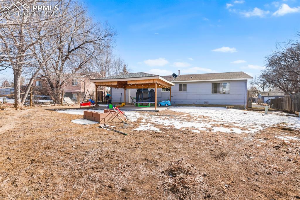 Snow covered back of property with a gazebo and a patio