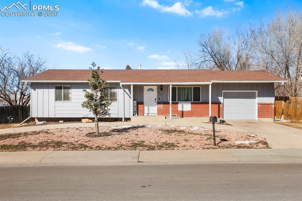 Ranch-style home with covered porch, brick siding, concrete driveway, board and batten siding, and a garage