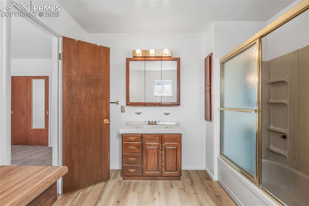 Full bathroom featuring vanity, light wood finished floors, and shower / bath combination with glass door