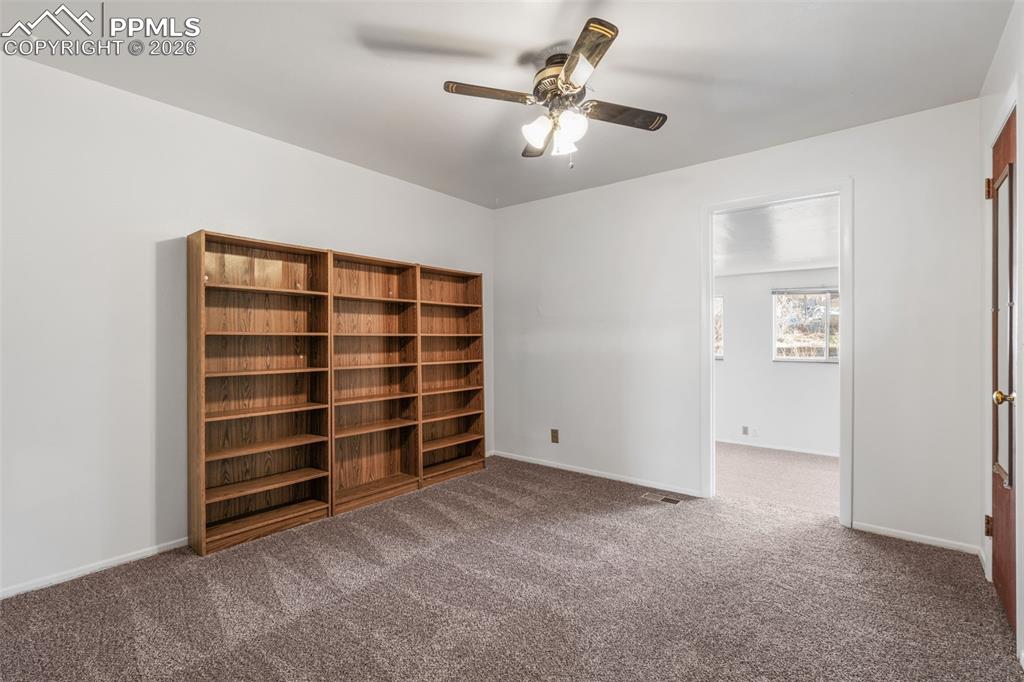 Non-conforming bedroom/office with bookshelves, ceiling fan & new carpet