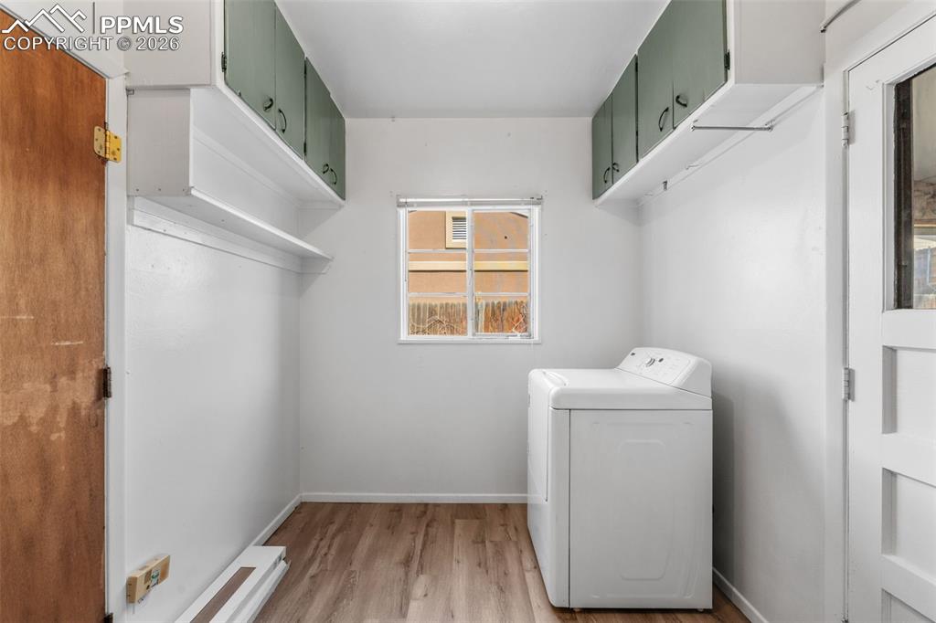 Laundry area with washer / dryer, light wood-style flooring, and cabinet space