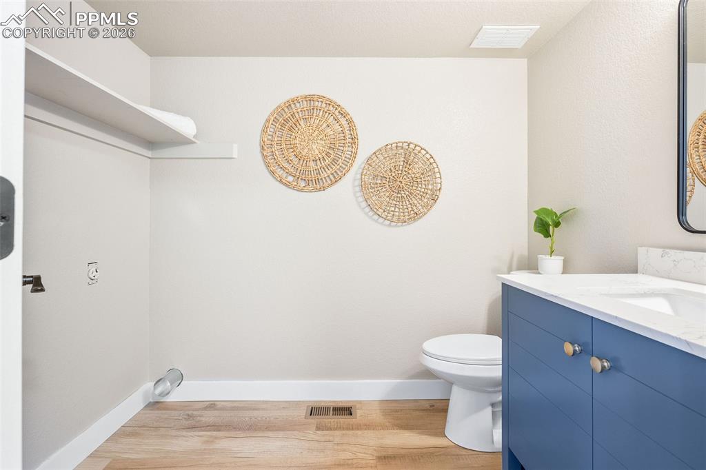Bathroom with vanity and light wood-style floors and laundry space 