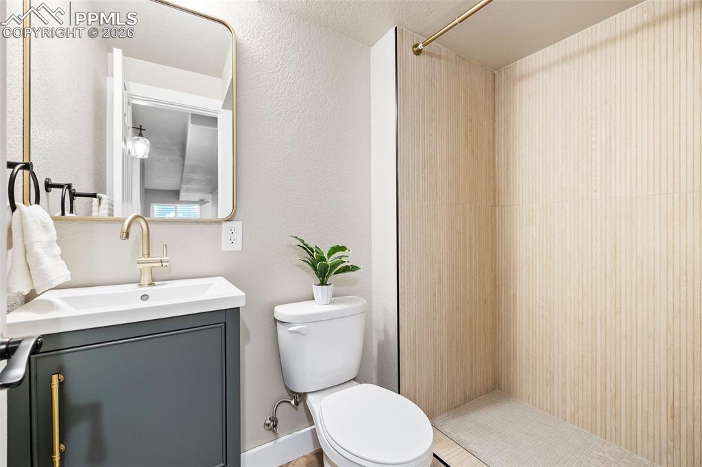 Bathroom featuring vanity, walk in shower, and a textured wall