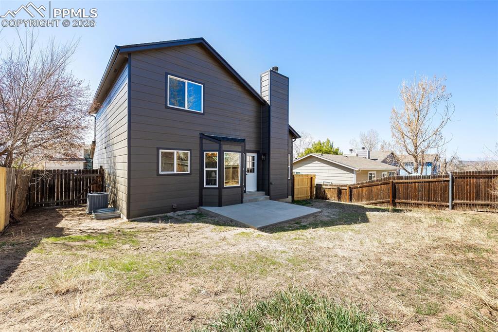 Rear view of house featuring a patio, a fenced backyard, and a chimney