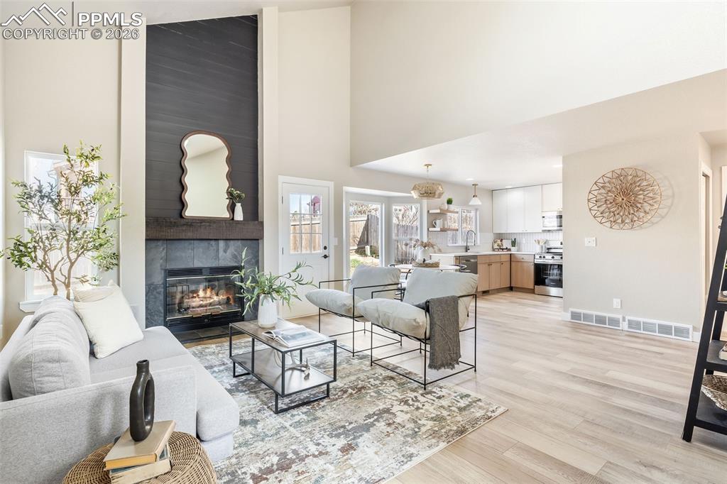 Living area with light wood-type flooring, a fireplace, and vaulted ceiling
