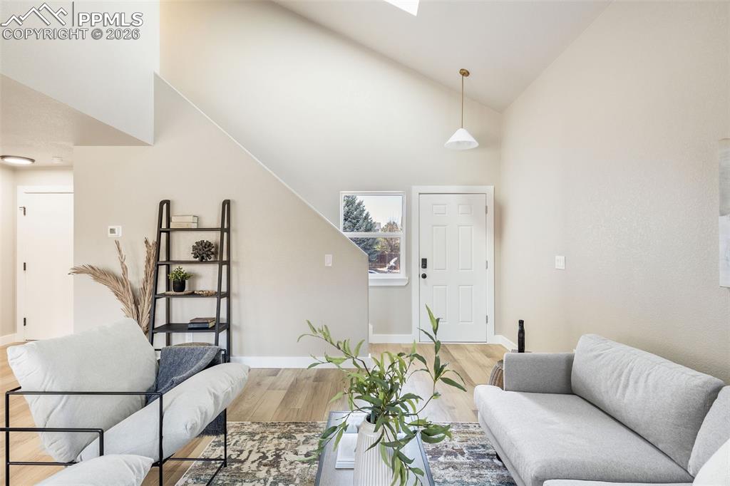 Living area featuring vaulted ceiling, a skylight, and light wood-style floors