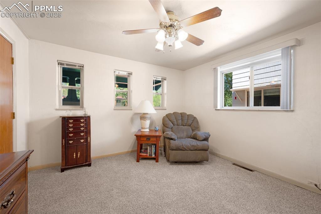 Living area featuring light colored carpet and ceiling fan