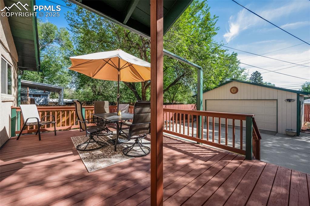Wooden terrace with an outdoor structure, outdoor dining space, and a garage