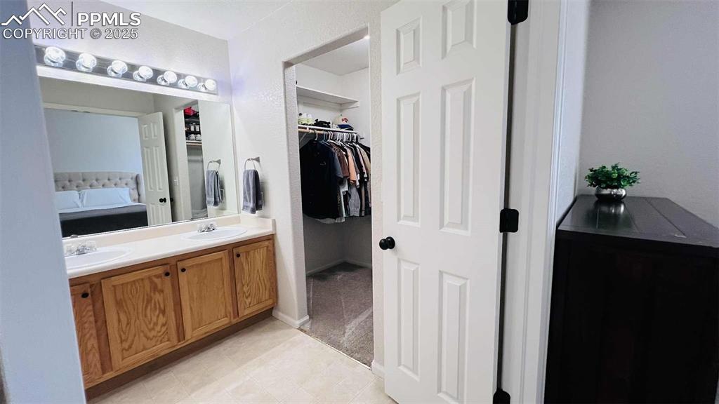 Full bathroom with double vanity and a walk in closet