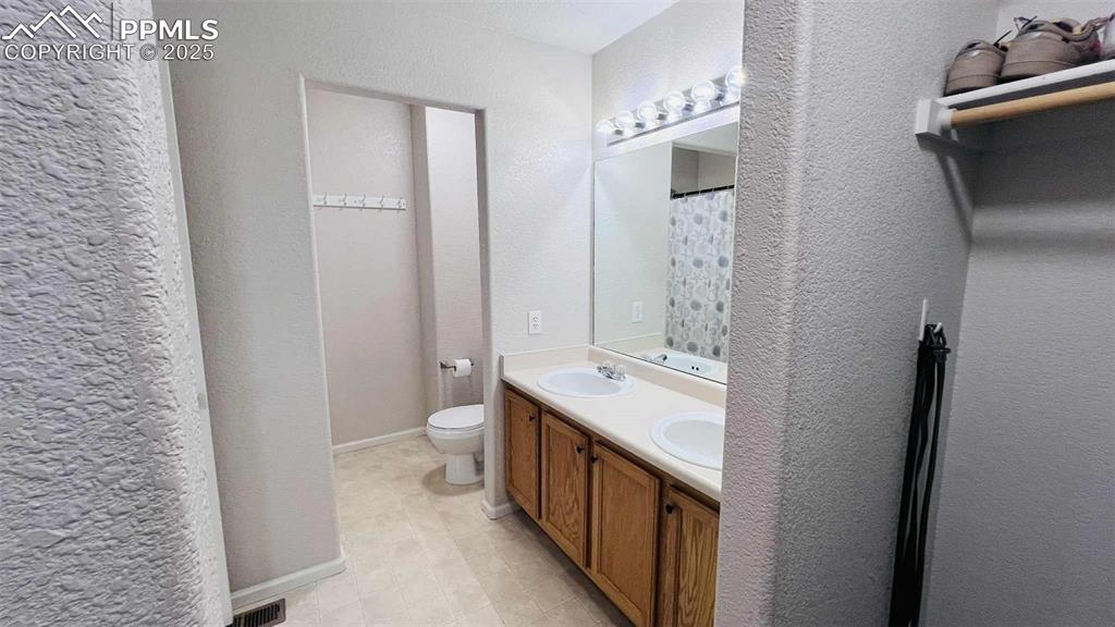 Bathroom with double vanity and a textured wall
