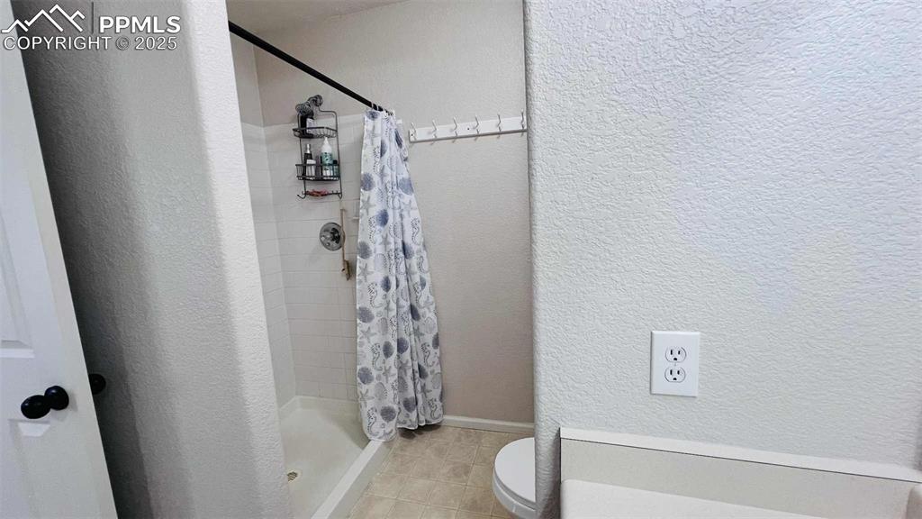 Full bathroom featuring a textured wall, a stall shower, and tile patterned flooring