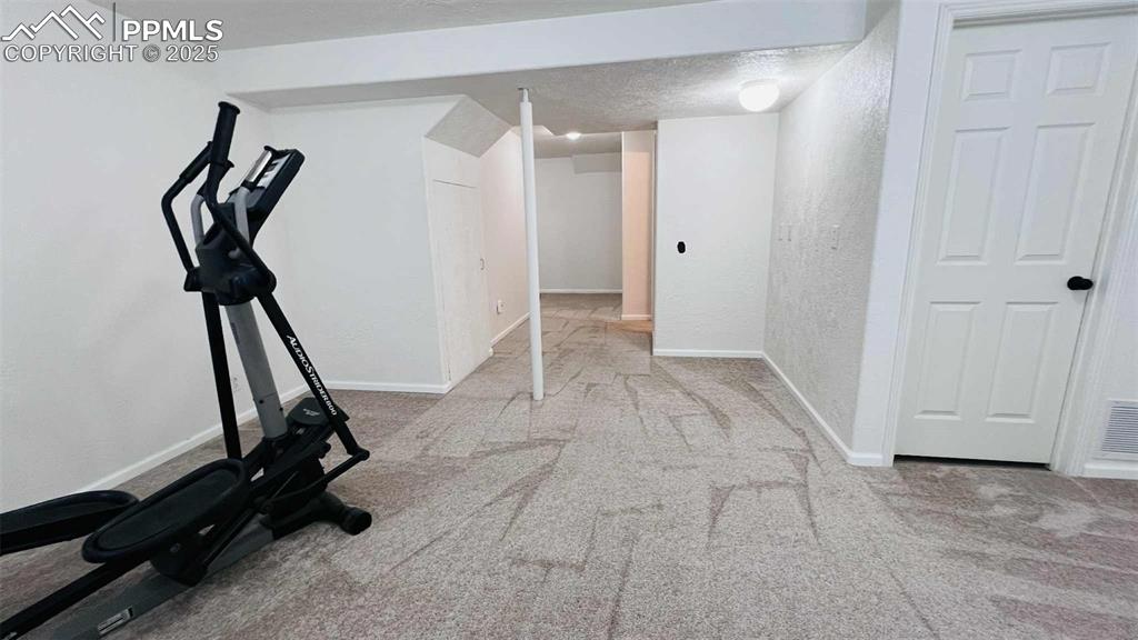 Workout room featuring carpet floors, a textured wall, and a textured ceiling
