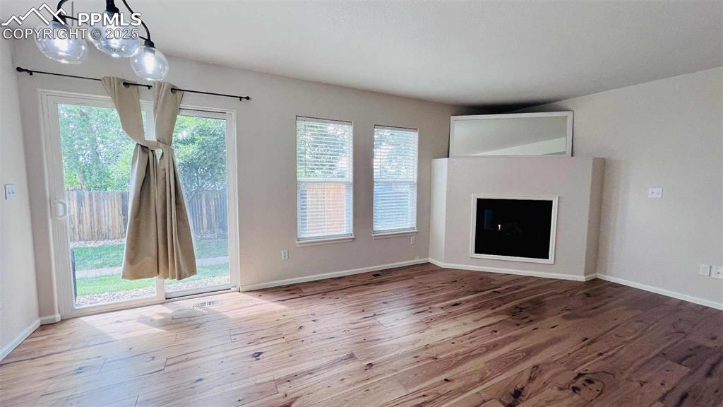 Unfurnished living room with wood-type flooring, a chandelier, and a fireplace