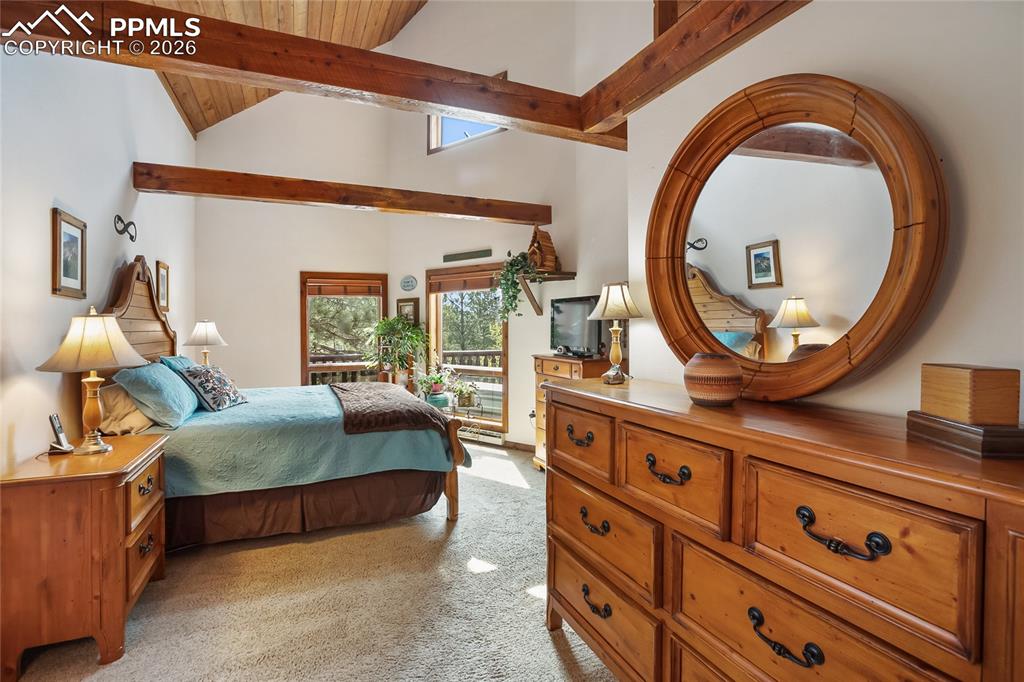 The main bedroom with light colored carpet and wooden vaulted ceiling and exposed beams!