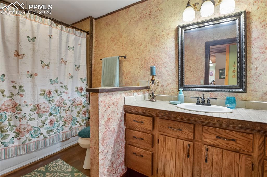 Bathroom featuring vanity, wooden crown molding, shower / bath combination, and dark wood flooring!