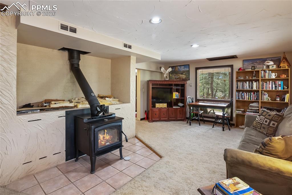 Tiled space in the family room with a wood stove, carpet floors, and recessed can lighting!