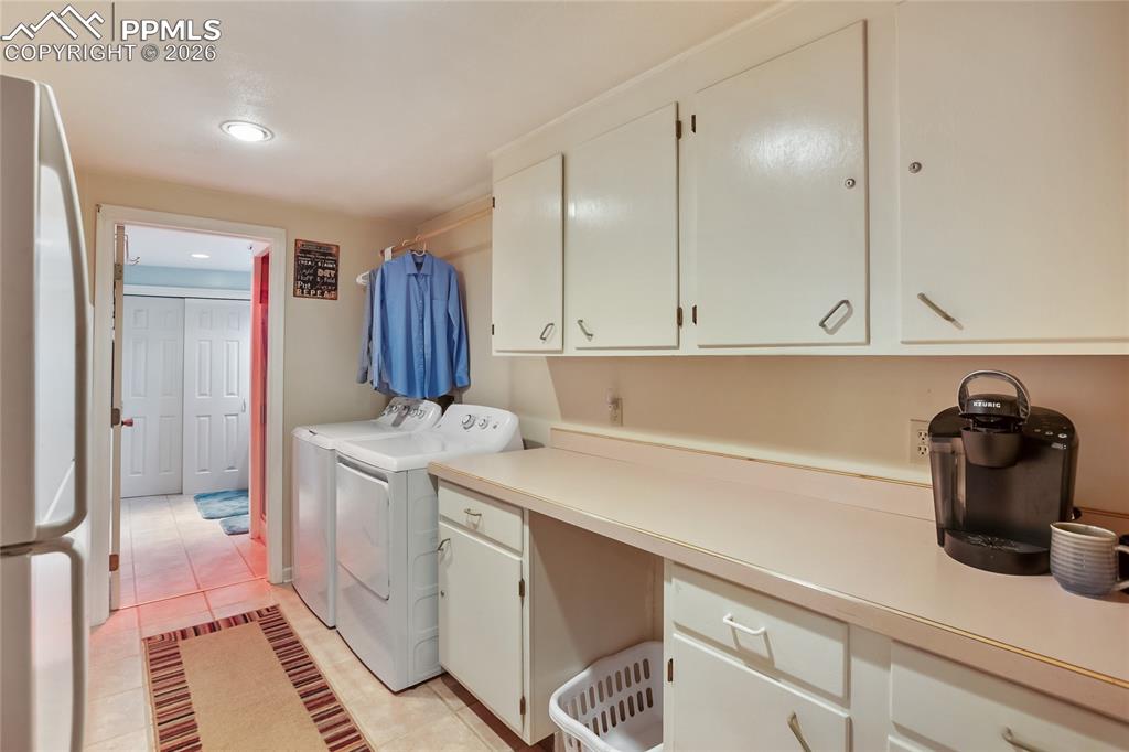 Laundry area with light tile patterned flooring, separate washer and dryer, recessed lighting, and cabinet space!