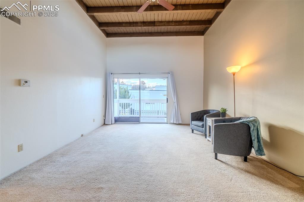 Living area featuring a wood ceiling with exposed beams, a towering ceiling, carpet floors, and ceiling fan