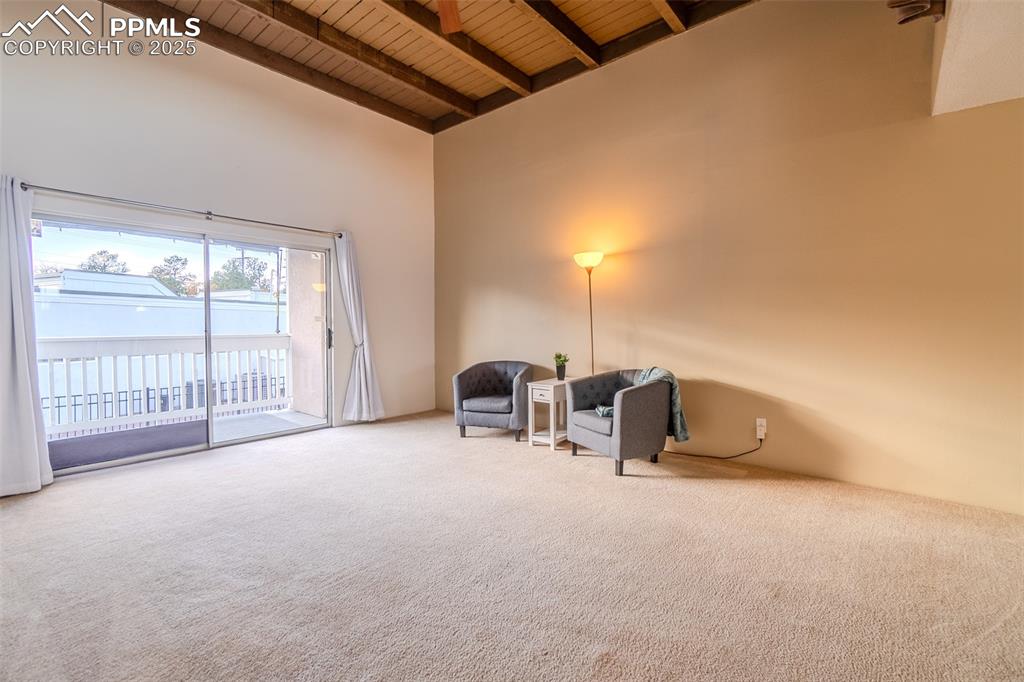 Unfurnished room featuring high vaulted ceiling, a wooden ceiling with exposed beams, and carpet flooring