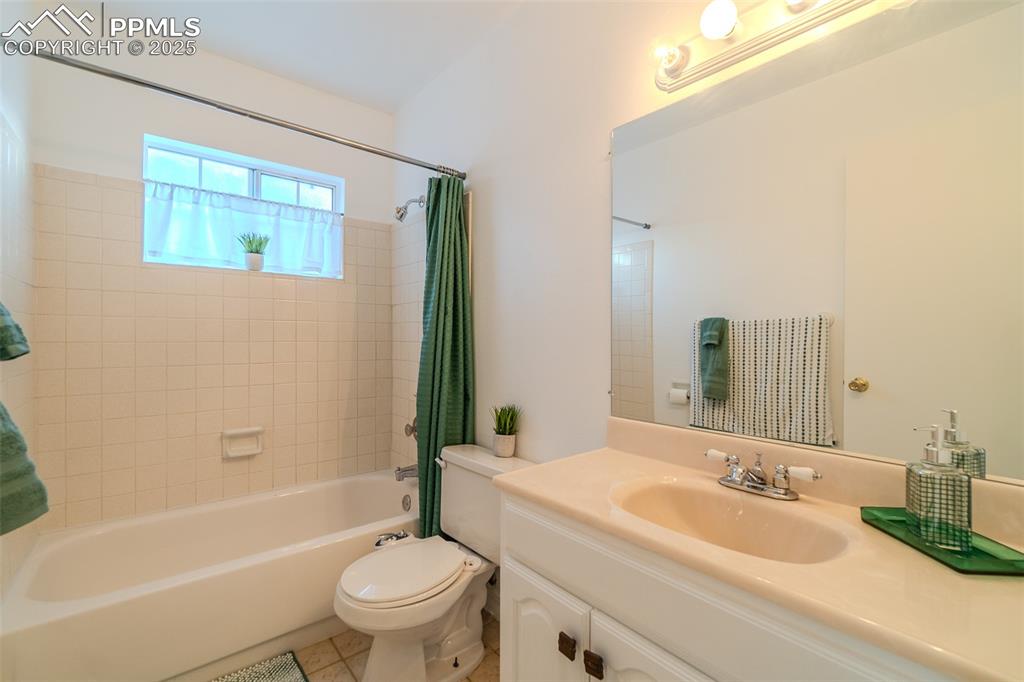 Bathroom with vanity, shower / bath combo with shower curtain, and light tile patterned flooring