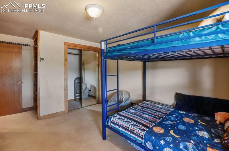 Bedroom featuring carpet, a closet, a textured ceiling, and baseboards