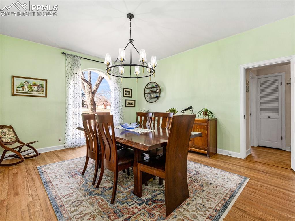 This formal dining room is complimented by a modern light fixture, floor to ceiling arched window and newly finished hardwood floors