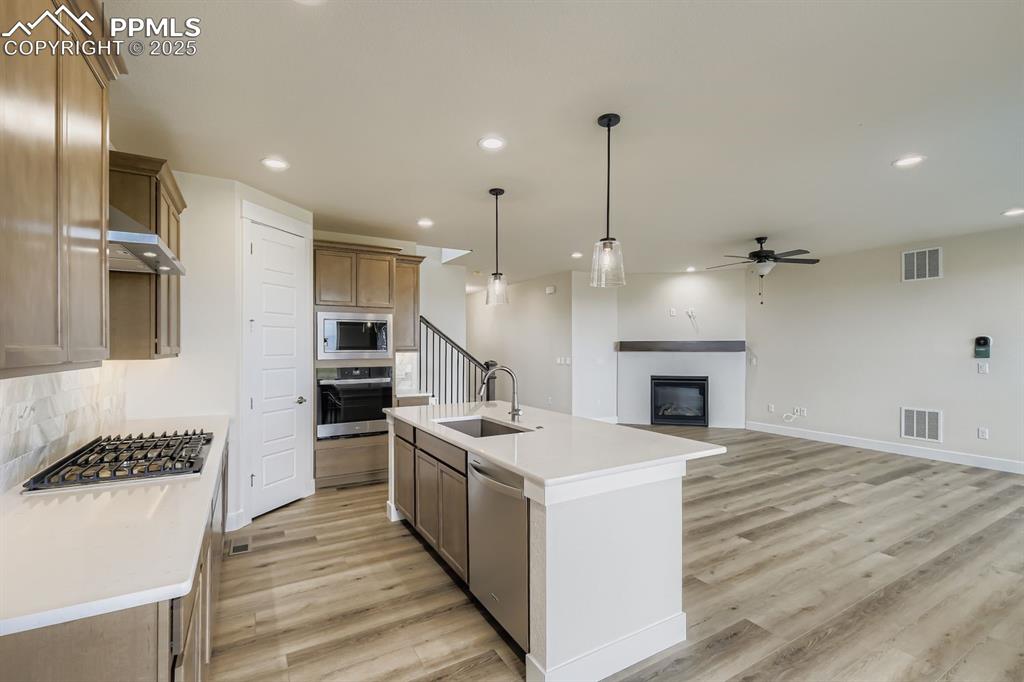 Kitchen with decorative light fixtures, a glass covered fireplace, ceiling fan, recessed lighting, and open floor plan