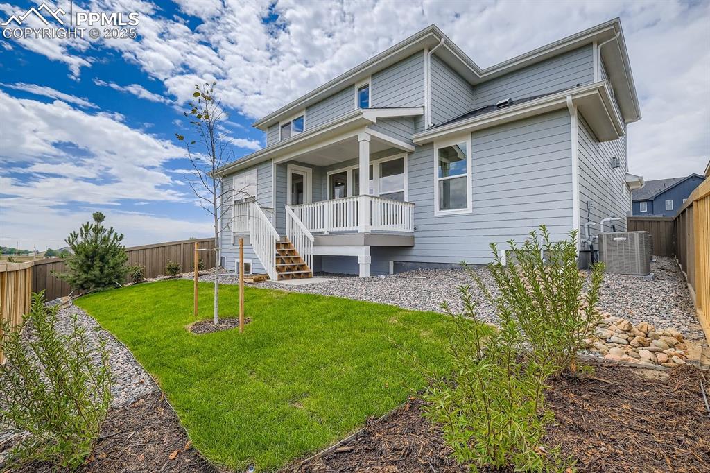Rear view of property featuring a fenced backyard and stairway