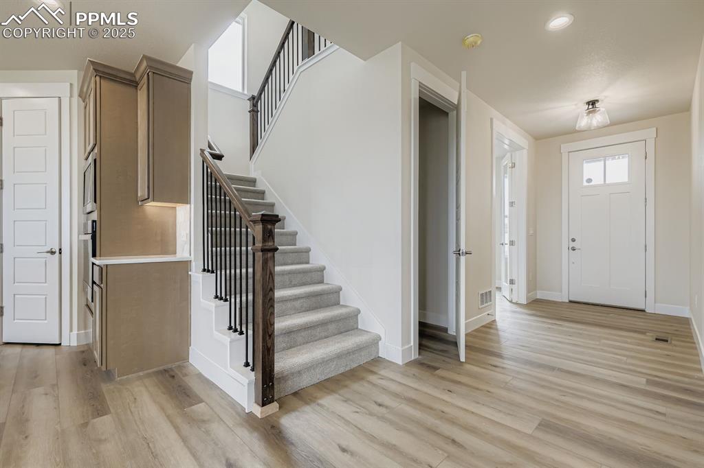 Entrance foyer featuring recessed lighting, healthy amount of natural light, stairway, and light wood-style flooring