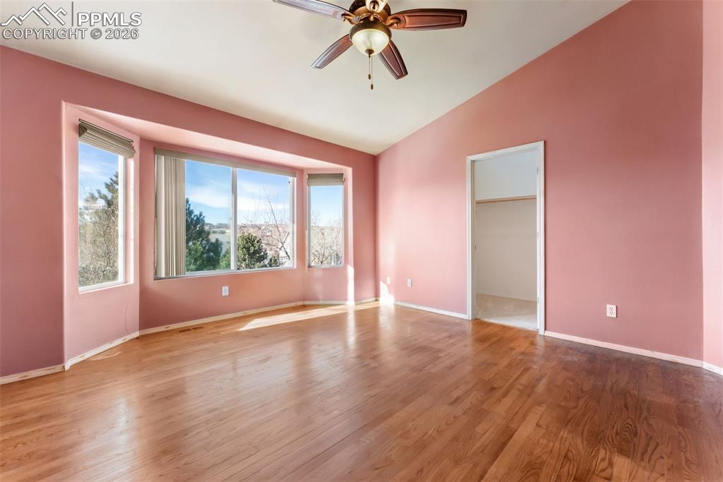 Empty room featuring wood finished floors, lofted ceiling, and a ceiling fan