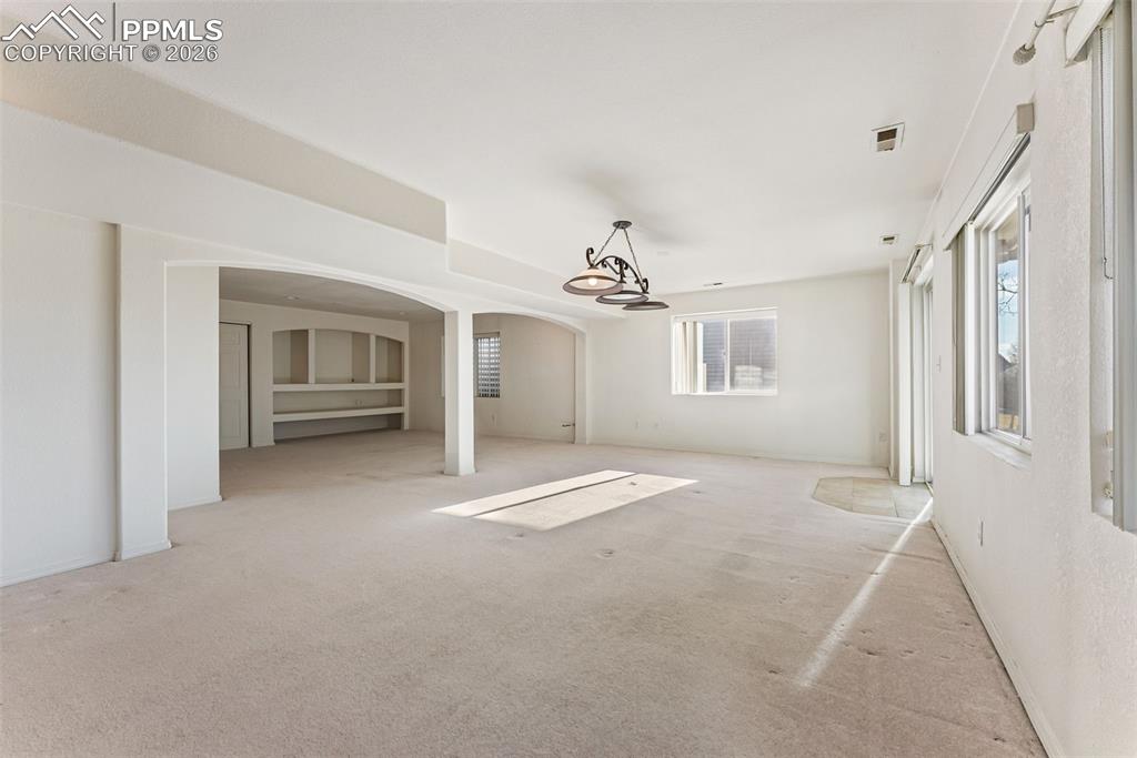 Unfurnished living room with arched walkways and carpet flooring