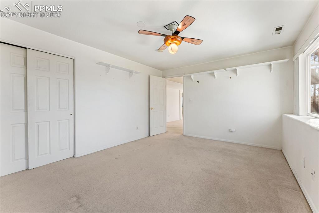 Unfurnished bedroom with carpet, a ceiling fan, and a closet