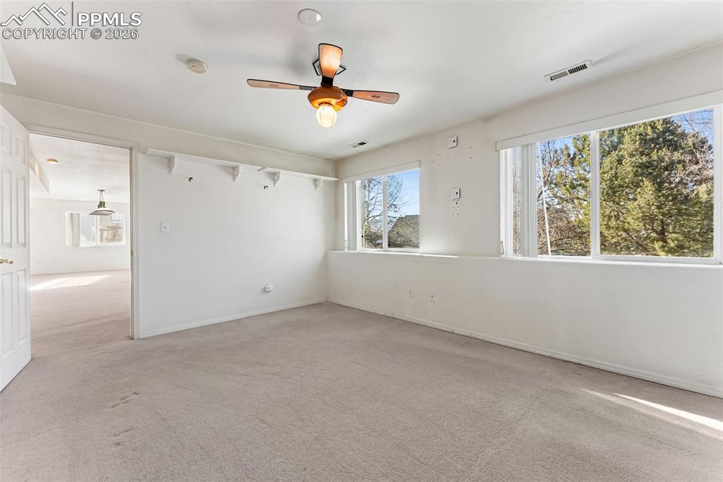 Empty room with ceiling fan and light carpet