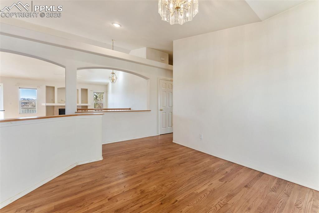 Unfurnished room featuring a chandelier, wood finished floors, and recessed lighting