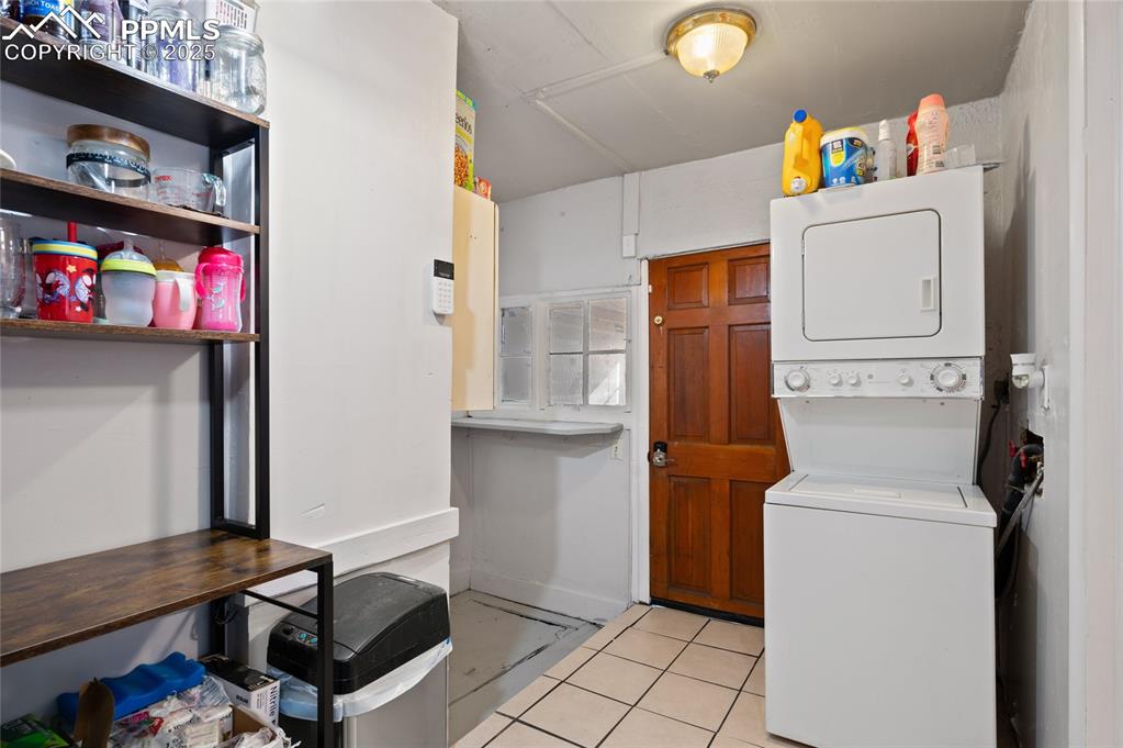 Laundry room featuring light tile patterned flooring and stacked washer / drying machine