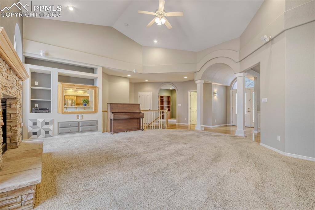 living room with built in features, carpet floors, ornate columns, arched walkways, and a fireplace