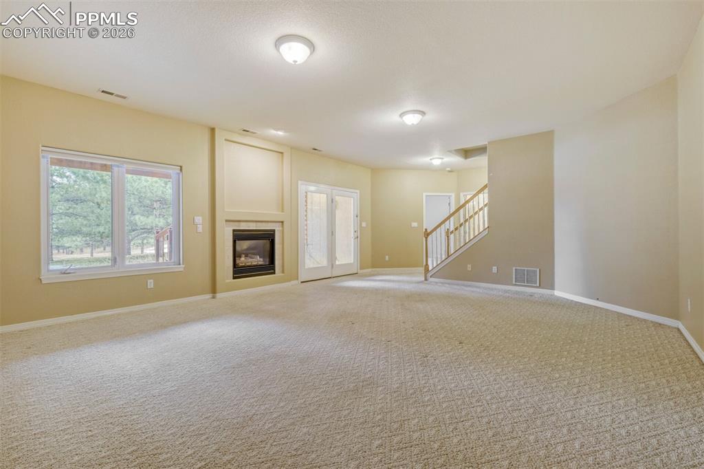 Family room with a tile fireplace and carpet flooring and walkout to covered patio