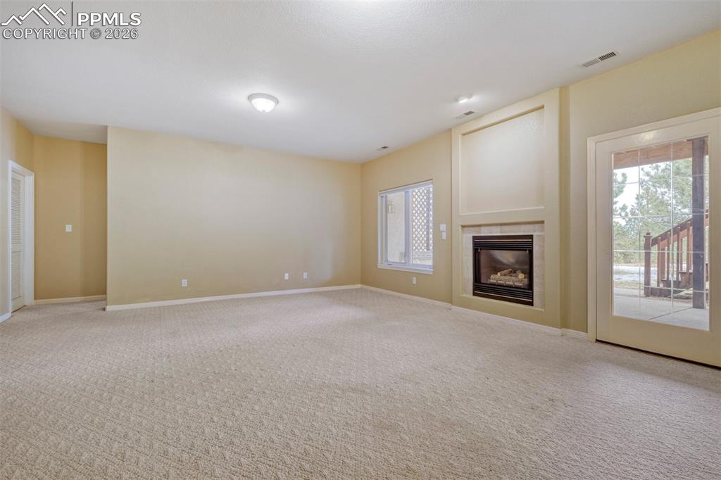 Family room with a tile fireplace and carpet flooring and walkout to covered patio