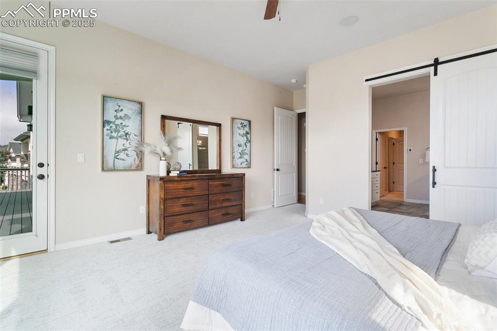 Bedroom with access to exterior, carpet floors, a barn door, and a ceiling fan