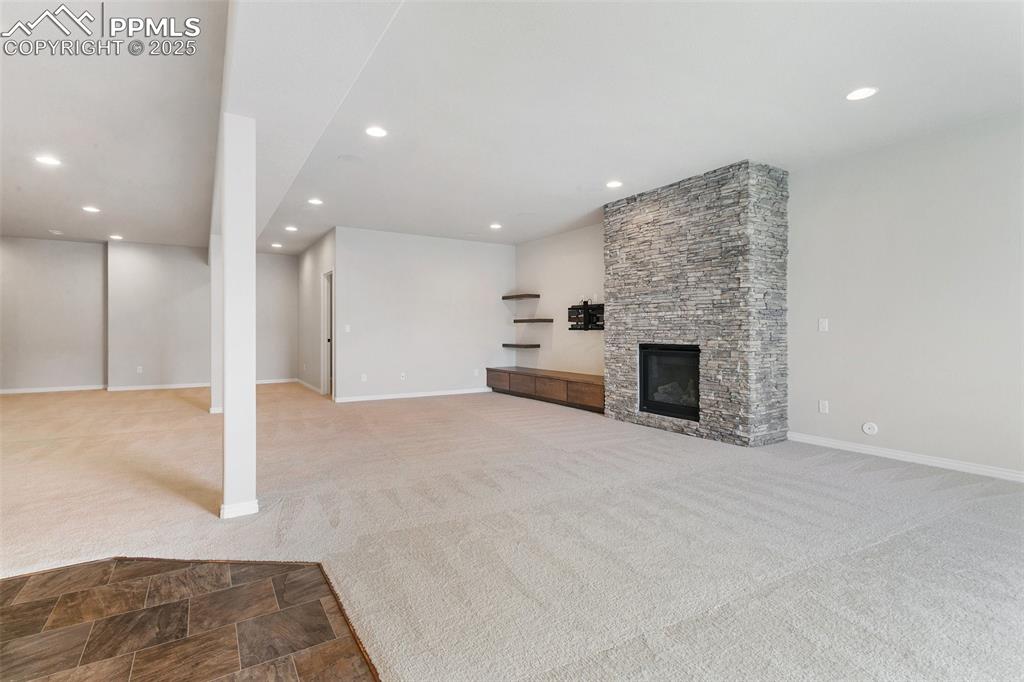 Unfurnished living room featuring carpet floors, recessed lighting, and a fireplace
