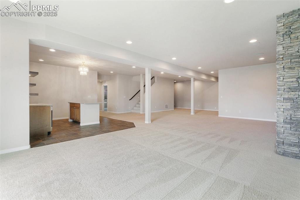 Finished basement with light carpet, recessed lighting, and stairway