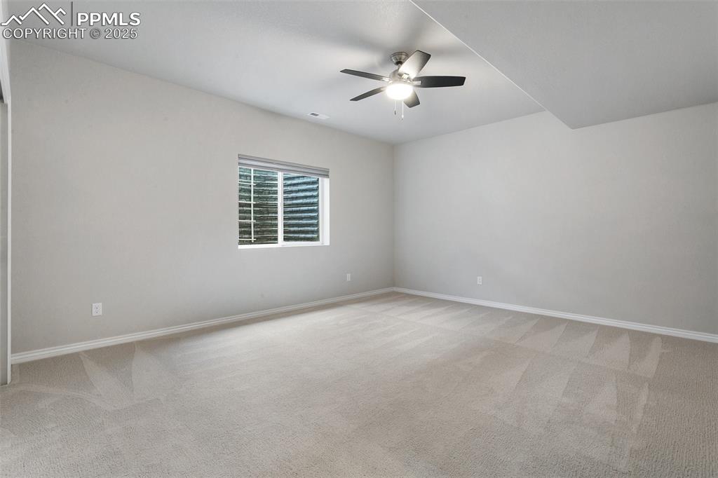 Empty room with ceiling fan and light colored carpet