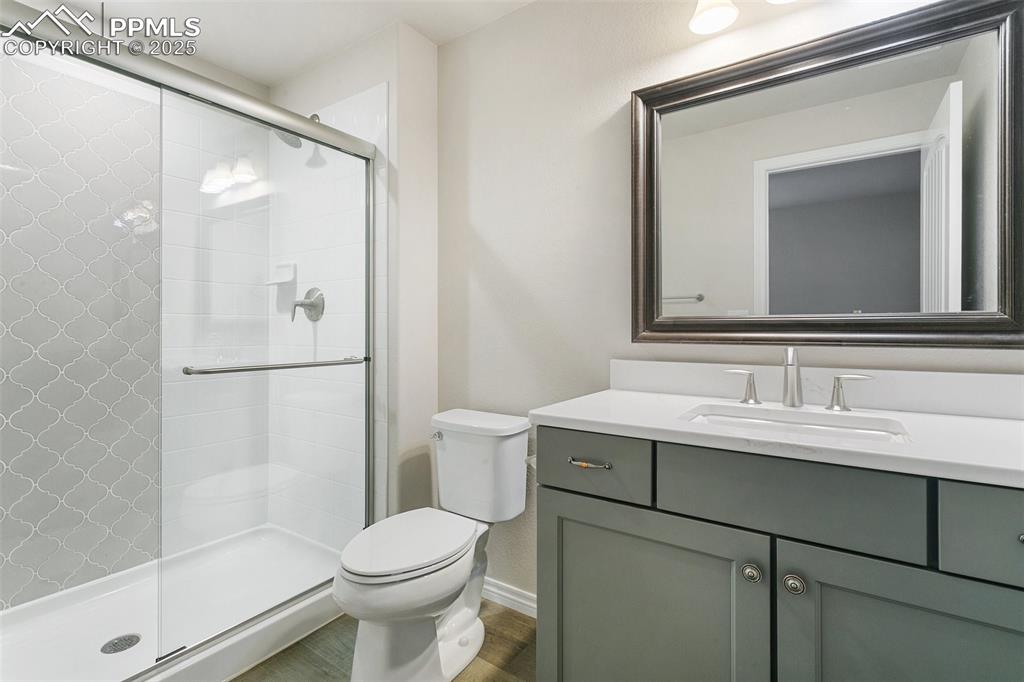 Full bathroom featuring vanity, a stall shower, and wood finished floors