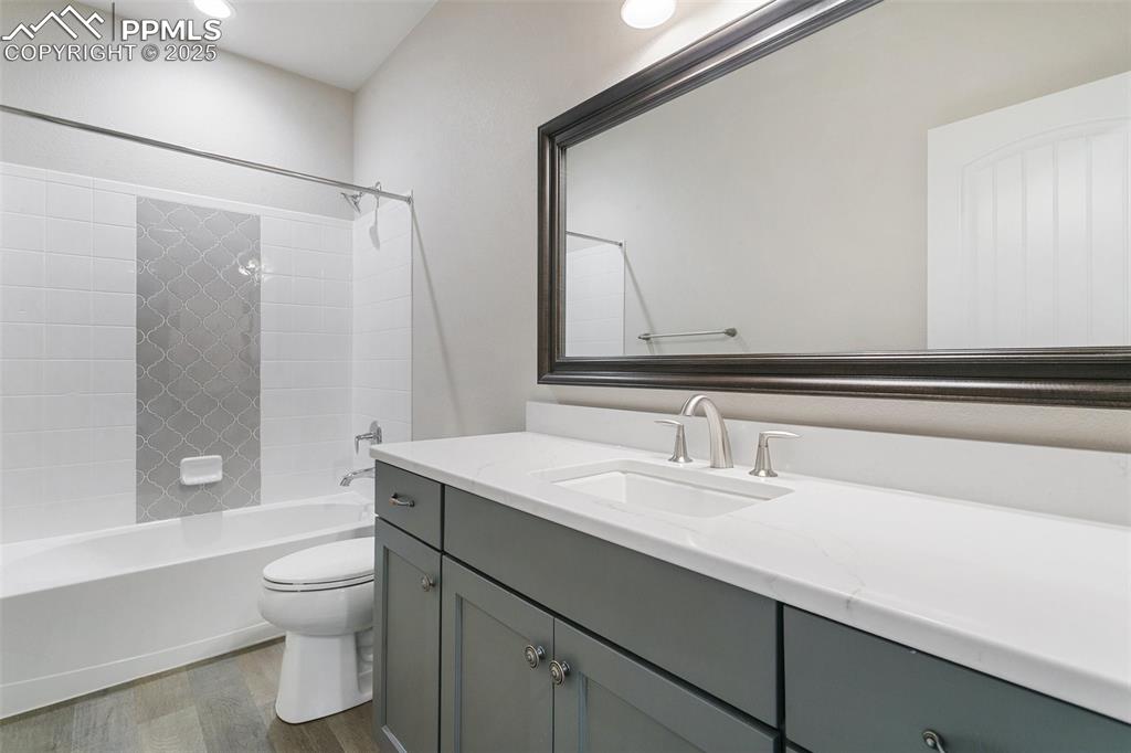 Bathroom with wood finished floors, vanity, bathing tub / shower combination, and recessed lighting